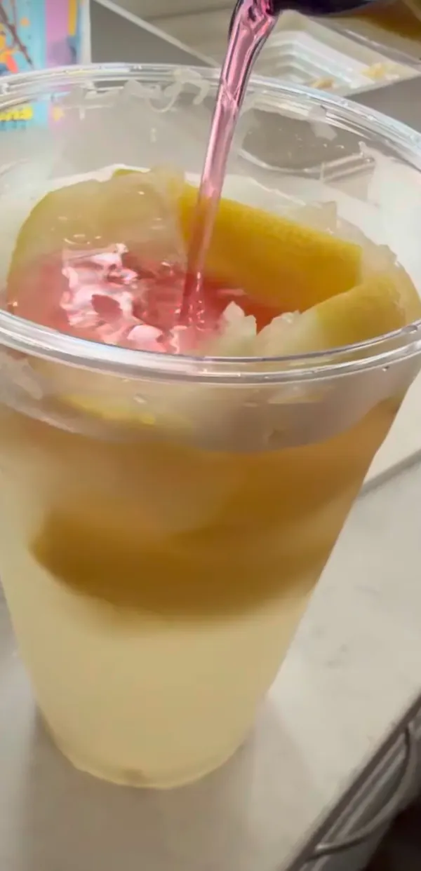 Pineapple lemonade in a clear cup topped with fresh pineapple.